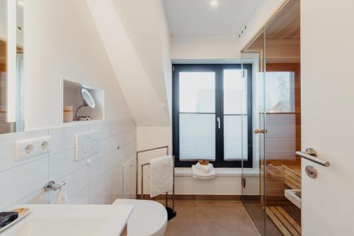 a white bathroom with a toilet and a window at SandDorn 1 und 2 in Pruchten
