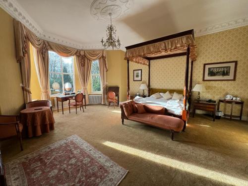 a bedroom with a canopy bed and a desk at Tre-Ysgawen Hall & Spa in Llangefni