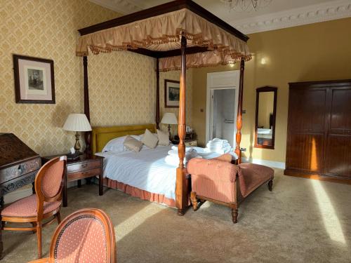 a bedroom with a canopy bed and a desk and chairs at Tre-Ysgawen Hall & Spa in Llangefni