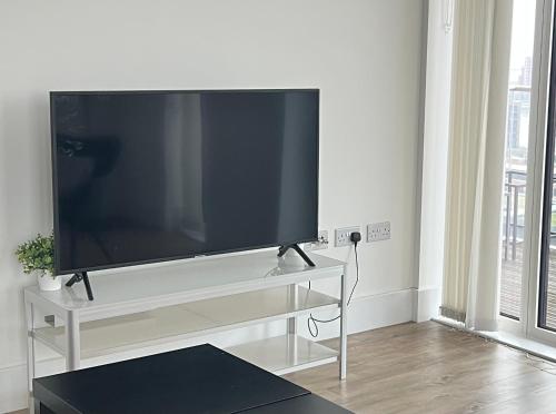 a flat screen tv sitting on a stand in a living room at Next to London City airport Apartments in Woolwich