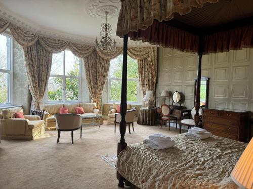 a bedroom with a canopy bed and a living room at Tre-Ysgawen Hall & Spa in Llangefni