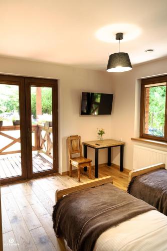 a bedroom with two beds and a table and a desk at Zarębisko - noclegi całoroczne in Zwierzyniec