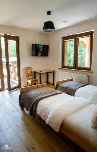 two beds in a room with a table and windows at Zarębisko - noclegi całoroczne in Zwierzyniec