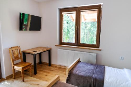 a bedroom with a bed and a table and a window at Zarębisko - noclegi całoroczne in Zwierzyniec