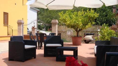 a patio with chairs and tables and an umbrella at Affitta camere Il Ruscello in Scheggino