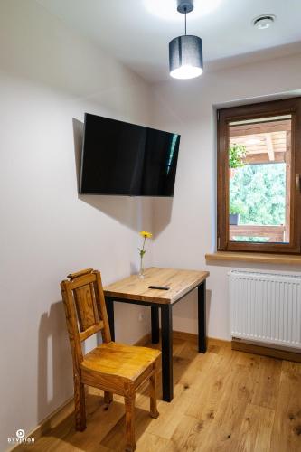 a table with a chair and a television on a wall at Zarębisko - noclegi całoroczne in Zwierzyniec