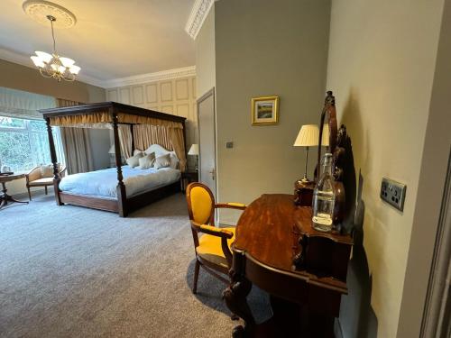 a bedroom with a bed and a wooden desk with a table at Tre-Ysgawen Hall & Spa in Llangefni