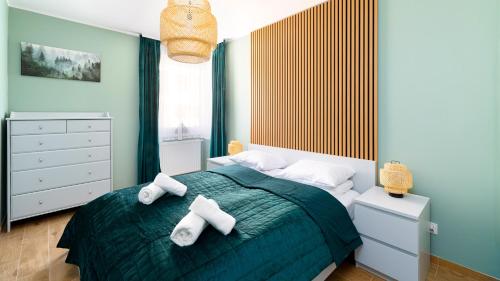een slaapkamer met een groen bed en handdoeken bij Apartament Leśny Karpacz in Karpacz