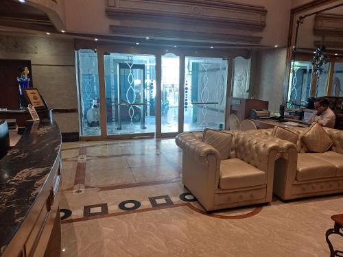 a living room with couches and a man sitting on a couch at Hotel Benzz Park Chennai in Chennai