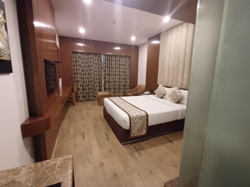 a bedroom with a large bed and a room with at Hotel Benzz Park Chennai in Chennai