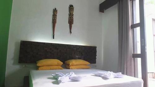 a bedroom with a white bed with yellow pillows at WHITE SANDS RESORT in Gili Trawangan