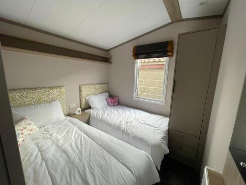 um pequeno quarto com 2 camas e uma janela em 2021 2 bedroom static caravan in 5 stars Patrington haven holiday park em Patrington