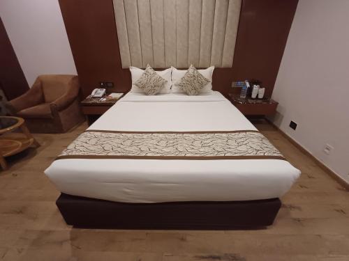 a bedroom with a large bed with white sheets and pillows at Hotel Benzz Park Chennai in Chennai