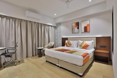a hotel room with a bed and a desk and a room at Hotel Elements Surat in Surat