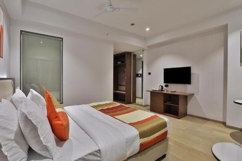 a hotel room with a bed and a television at Hotel Elements Surat in Surat