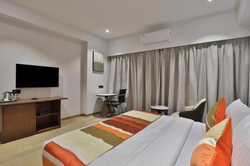 a hotel room with a bed and a flat screen tv at Hotel Elements Surat in Surat