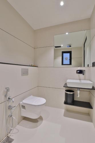 a white bathroom with a toilet and a sink at Hotel Elements Surat in Surat