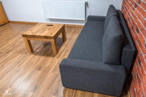 a couch against a brick wall next to a coffee table at Zarębisko - noclegi całoroczne in Zwierzyniec