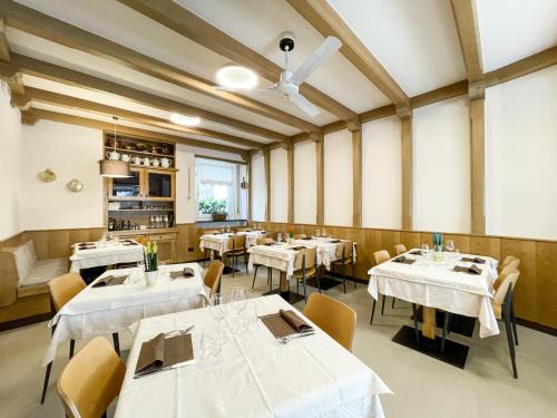 uma sala de jantar com mesas e cadeiras brancas em Hotel Locanda Alla Perla em Ledro