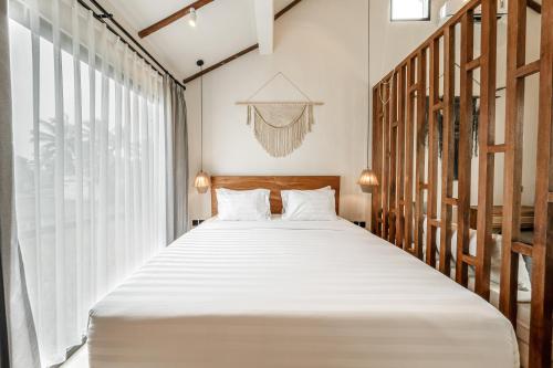 a bedroom with a large bed with white sheets at Sarang Apartments by EVDEkimi in Ubud