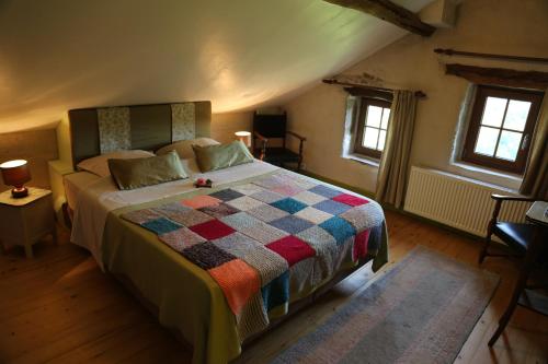 a bedroom with a bed with a colorful quilt at Les Grandes Fontaines in La Longine