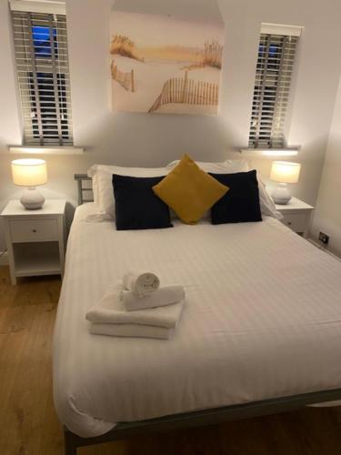 - une chambre avec un lit blanc et des serviettes dans l'établissement Just Stay Wales - Marshmallow Cottage, Oxwich, à Swansea