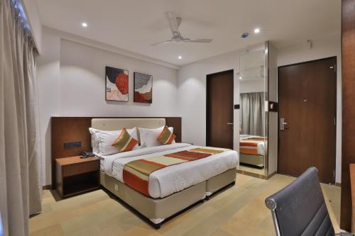 Habitación de hotel con cama y silla en Hotel Elements Surat, en Surat