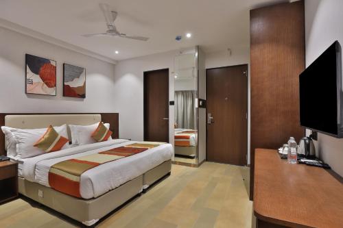 a bedroom with a bed and a flat screen tv at Hotel Elements Surat in Surat