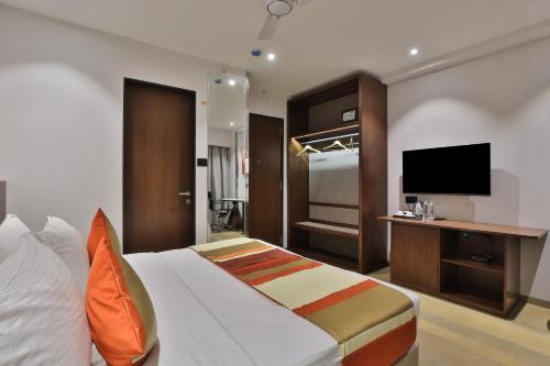 a hotel room with a bed and a flat screen tv at Hotel Elements Surat in Surat