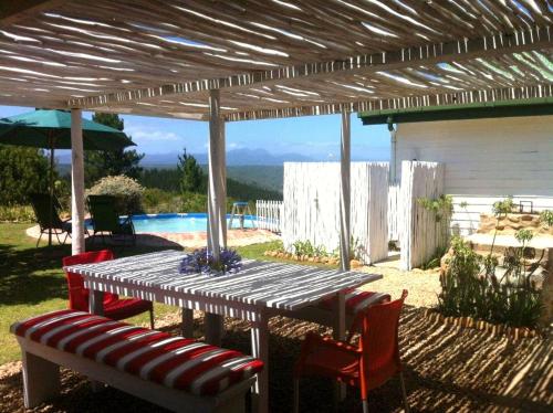 a wooden table and chairs under a pergola at Protea Wilds Retreat in Harkerville