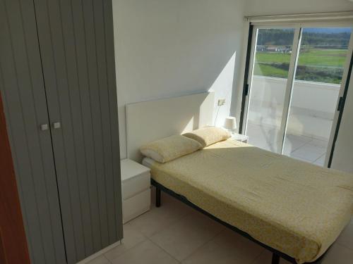 um pequeno quarto com uma cama e uma janela em ATICO AL LADO DEL MAR em Barreiros