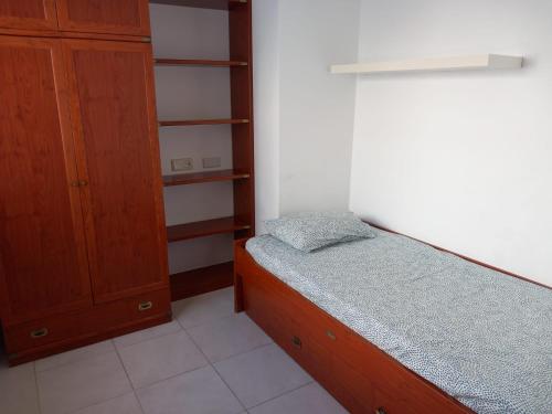 um quarto com uma cama e um armário de madeira em ATICO AL LADO DEL MAR em Barreiros