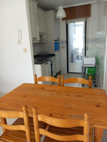 uma mesa de madeira e cadeiras numa cozinha em ATICO AL LADO DEL MAR em Barreiros