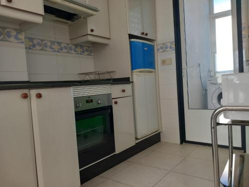 uma cozinha com armários brancos, um forno e um frigorífico em ATICO AL LADO DEL MAR em Barreiros