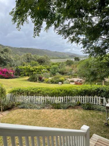 a white fence with a view of a garden at Beside Still Waters in Wilderness