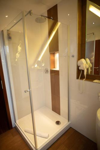 um chuveiro com uma porta de vidro na casa de banho em Vier Jahreszeiten Rooms em Husum