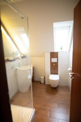 a bathroom with a toilet and a sink and a window at Vier Jahreszeiten Rooms in Husum