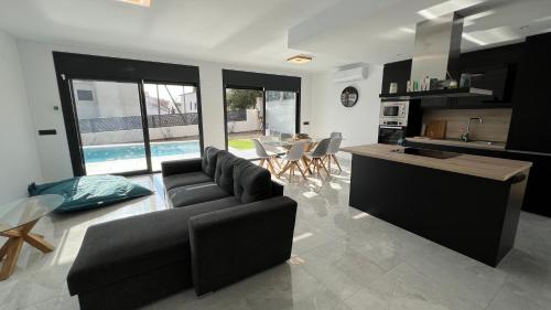 eine Küche und ein Wohnzimmer mit einem Sofa und einem Tisch in der Unterkunft Casa moderna Roses con piscina y jardin Mas Bosca, Roses in Palau-Saverdera