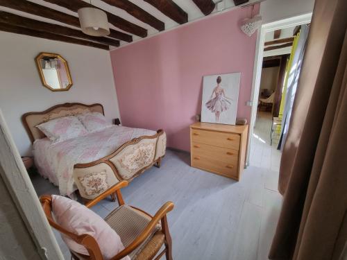 une chambre avec un lit, une commode et une chaise dans l'établissement La tourelle de la chaumière, à Goupillières