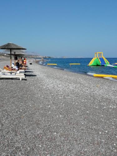 a beach with people sitting on chairs and umbrellas at Katerina Villa In Kiotari in Kiotari