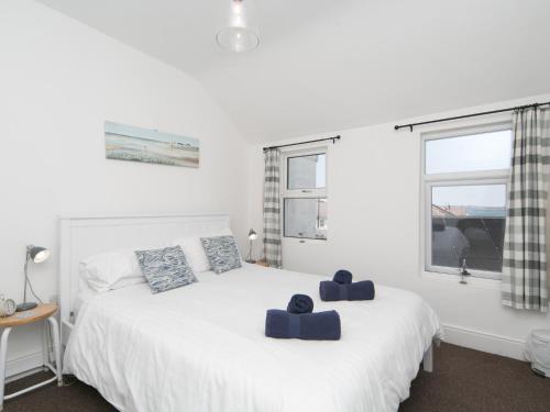 a bedroom with a white bed with blue pillows on it at Pass the Keys Breeze Cottage 2 bed Beach property in Rhosneigr