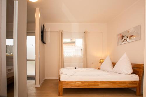 Schlafzimmer mit einem Bett mit weißer Bettwäsche und einem Fenster in der Unterkunft Hotel Hervest in Dorsten