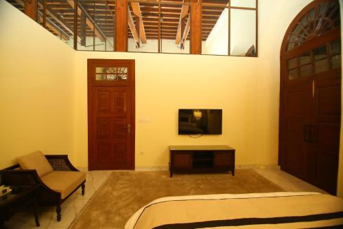 a room with a bed and a tv and a door at Peshawar Barracks Hotel Estb-1867 in Peshawar