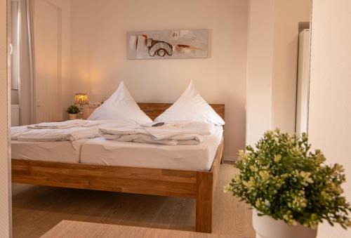 Schlafzimmer mit einem Bett mit weißer Bettwäsche und Kissen in der Unterkunft Hotel Hervest in Dorsten