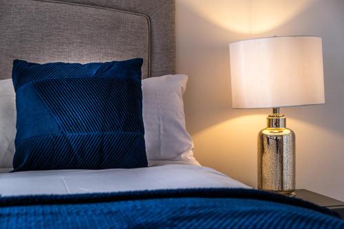 uma cama com uma almofada azul e um candeeiro sobre uma mesa em Broadway Mailbox Luxury New 1 Bed Apartment with Free Parking em Birmingham