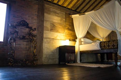 a bedroom with a canopy bed and a brick wall at Wahyu Private Peaceful Two Br Rustic Villa W Pool in Seminyak