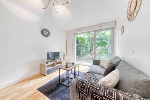 ein Wohnzimmer mit einem Sofa und einem TV in der Unterkunft Appartement moderne, Metro 7, Parking et Jardin in Villejuif