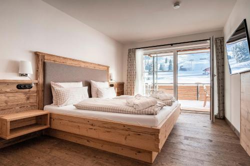 um quarto com uma cama grande e uma janela grande em Alpin Lodges - Moderne Appartements mit Zugang zu 3000 qm SPA Panoramahotel Oberjoch em Bad Hindelang