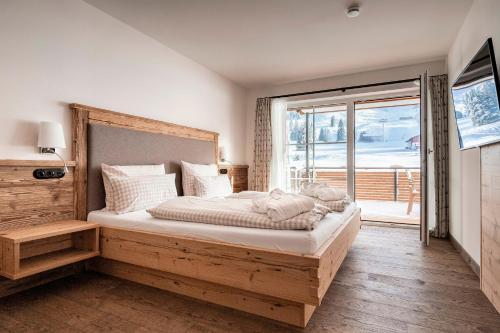 a bedroom with a large bed and a large window at Alpin Lodges - Moderne Appartements mit Zugang zu 3000 qm SPA Panoramahotel Oberjoch in Bad Hindelang