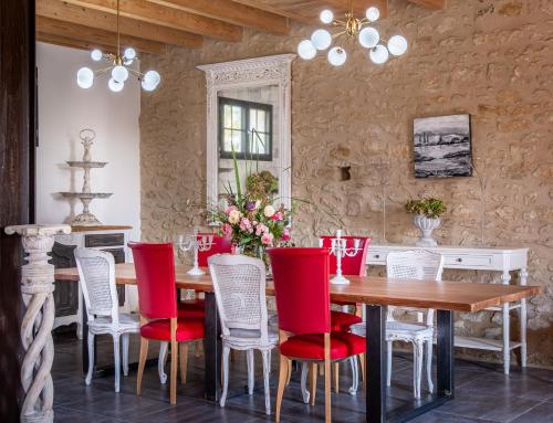 uma sala de jantar com uma mesa de madeira e cadeiras vermelhas em Le Hameau de la Closerie 